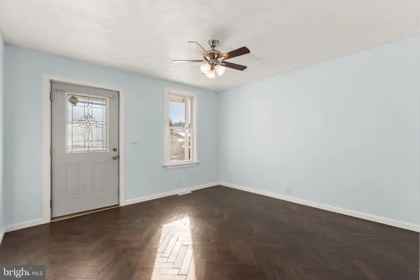 an empty room with wooden floor fan and windows