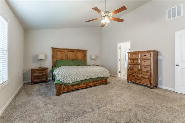 a spacious bedroom with a bed a dresser and a chandelier