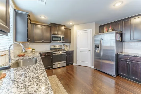 a kitchen with stainless steel appliances granite countertop a refrigerator stove and sink