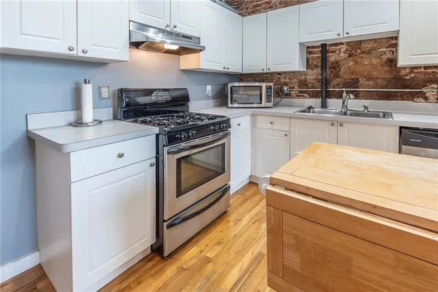a kitchen with cabinets appliances and a wooden floor