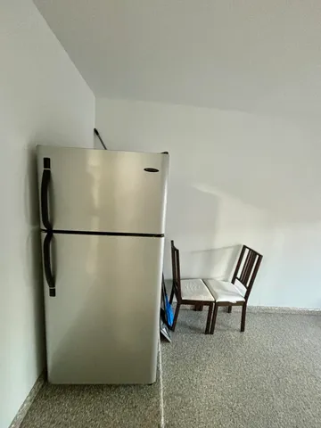 a view of an empty room with wooden floor and a refrigerator