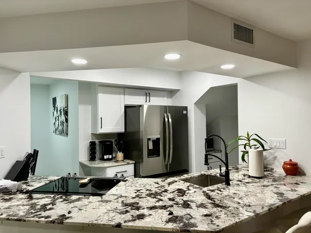 a kitchen with stainless steel appliances kitchen island granite countertop a refrigerator and a stove top oven