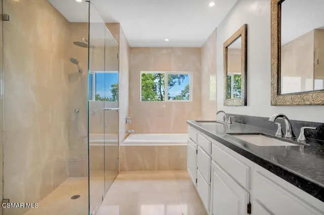 a bathroom with a granite countertop sink a mirror a bathtub and next to a window