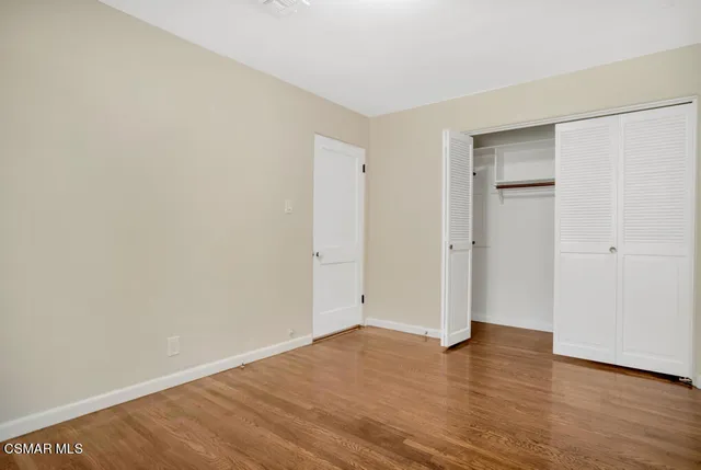 a view of an empty room with wooden floor and closet