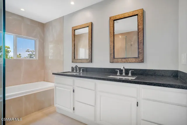 a bathroom with a granite countertop sink mirror and bathtub
