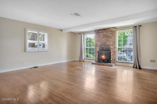 an empty room with windows fireplace and wooden floor