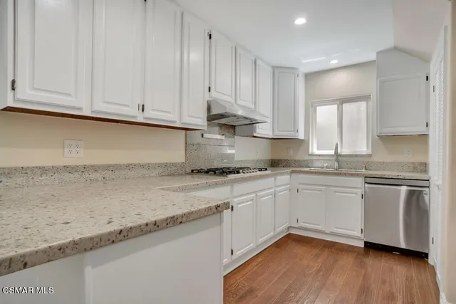 a kitchen with granite countertop stainless steel appliances white cabinets granite counter tops and a hard wood floors