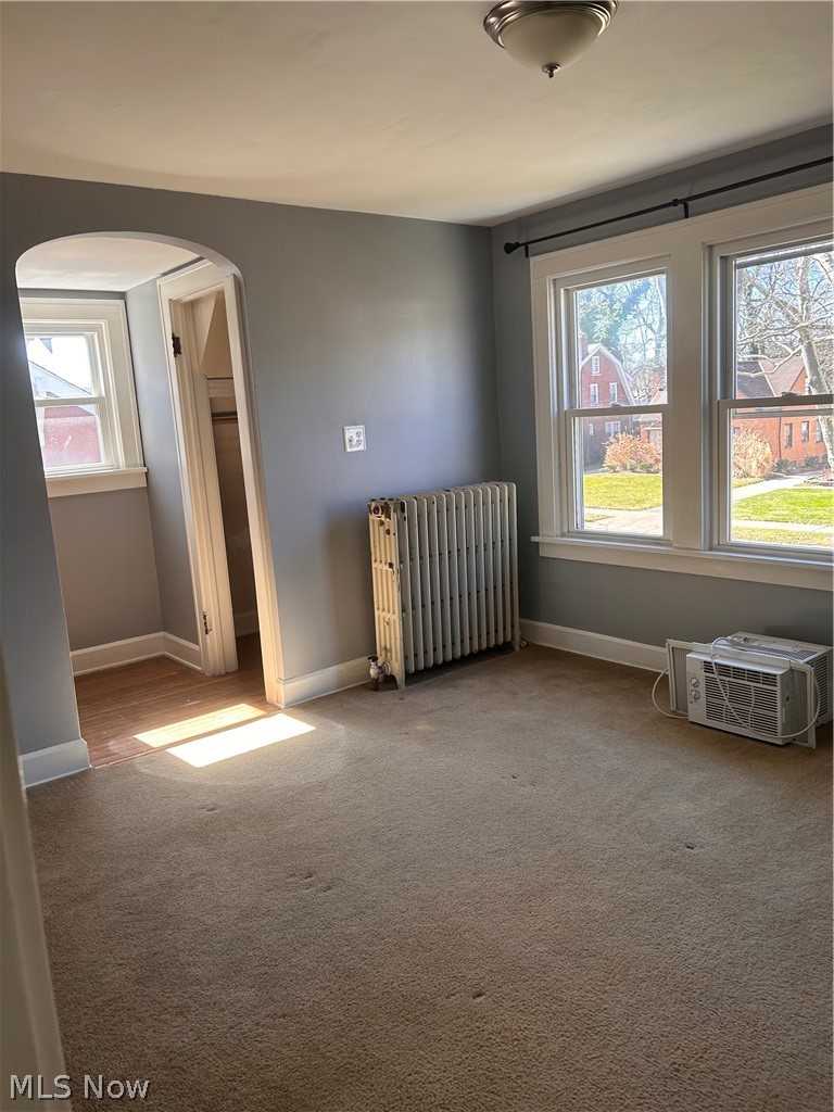 1001 Englewood Road Cleveland Heights, OH 44121 - Photo 16 of 28 Unfurnished room featuring radiator heating unit, arched walkways, and light carpet