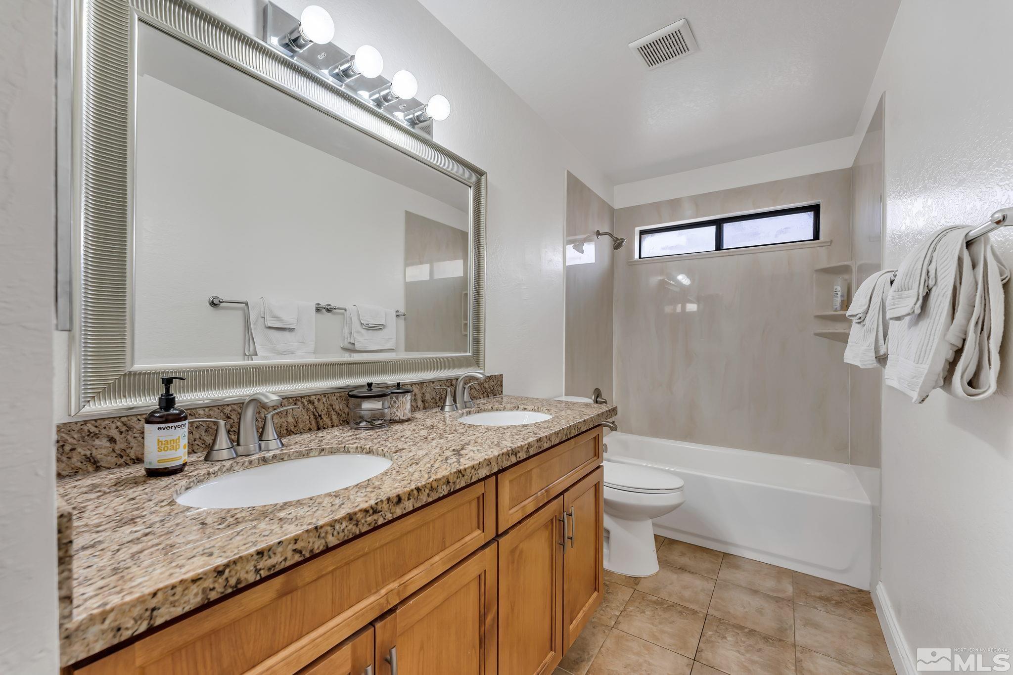 1802 Grand Point Way Reno, NV 89523 - Photo 13 of 19 a bathroom with a granite countertop sink a mirror a bathtub and shower