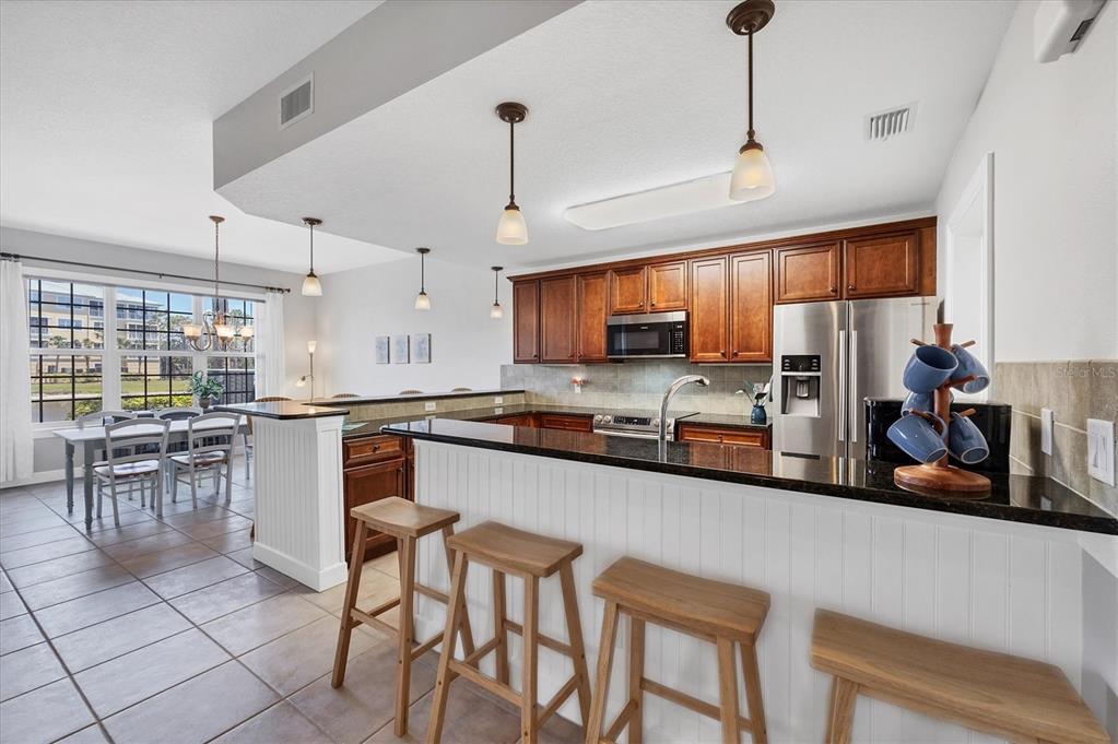 10720 Lemon Creek Loop, Unit 103 Englewood, FL 34224 - Photo 11 of 50 a kitchen with stainless steel appliances granite countertop a stove top oven a refrigerator a sink and chairs