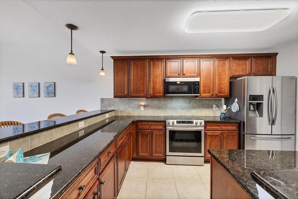 10720 Lemon Creek Loop, Unit 103 Englewood, FL 34224 - Photo 12 of 50 a kitchen with stainless steel appliances granite countertop a stove a sink and a microwave
