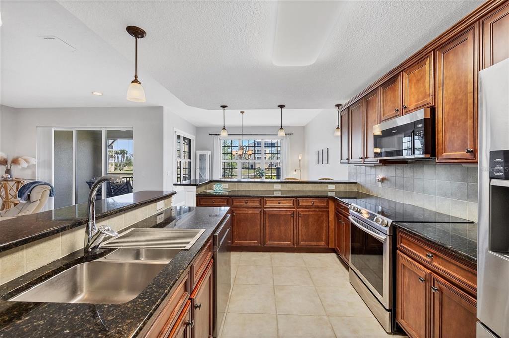 10720 Lemon Creek Loop, Unit 103 Englewood, FL 34224 - Photo 13 of 50 a kitchen with stainless steel appliances granite countertop a sink stove and refrigerator