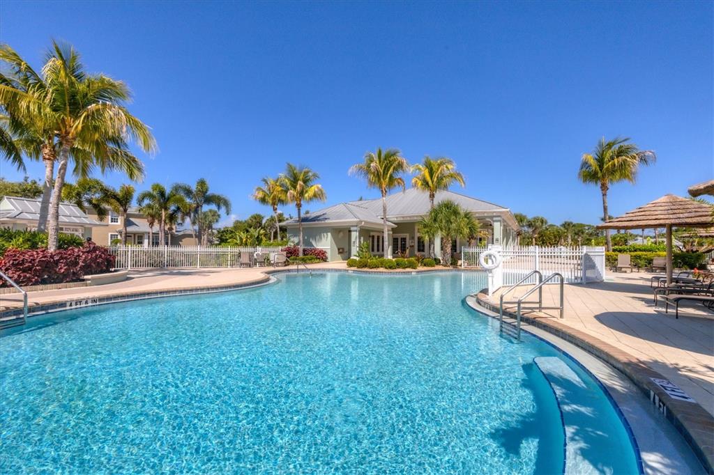 10720 Lemon Creek Loop, Unit 103 Englewood, FL 34224 - Photo 44 of 50 a view of a swimming pool with a lawn chairs under an umbrella