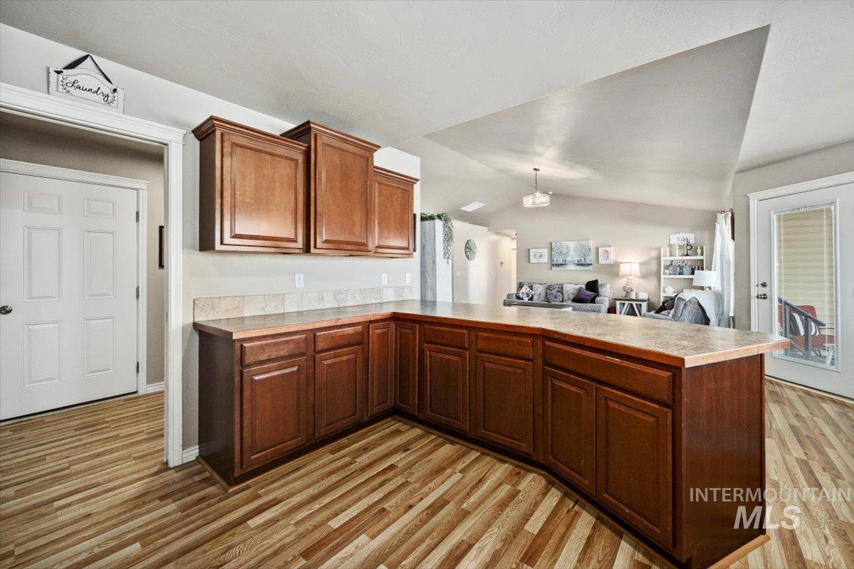 657 Creekside Way Twin Falls, ID 83301 - Photo 13 of 45 Kitchen featuring light countertops, vaulted ceiling, decorative light fixtures, a peninsula, and light wood finished floors