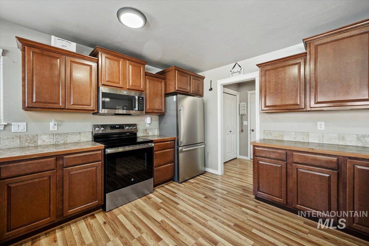 657 Creekside Way Twin Falls, ID 83301 - Photo 14 of 45 Kitchen with appliances with stainless steel finishes, light countertops, light wood finished floors, and brown cabinetry