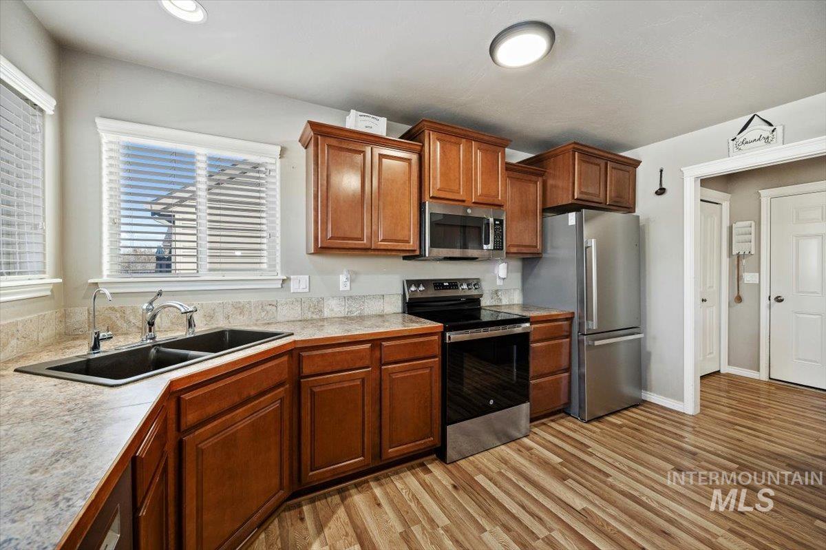 657 Creekside Way Twin Falls, ID 83301 - Photo 17 of 45 Kitchen featuring light countertops, stainless steel appliances, brown cabinetry, and light wood-style flooring