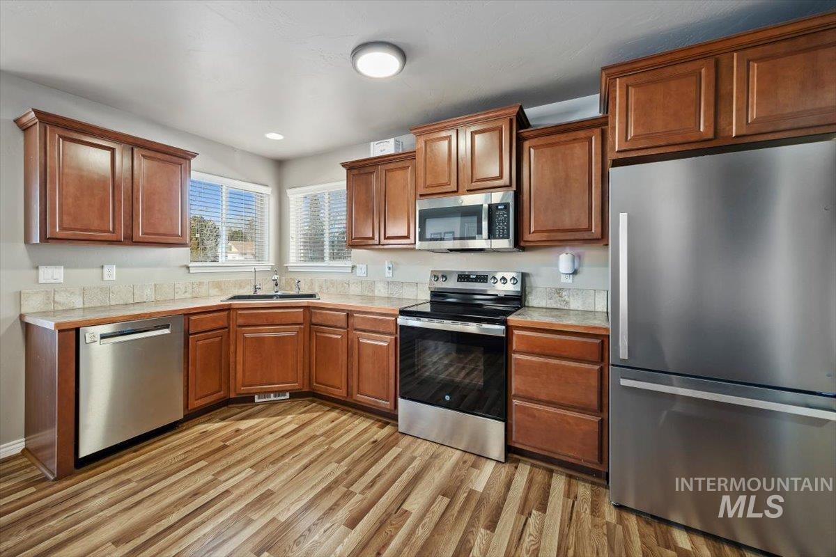 657 Creekside Way Twin Falls, ID 83301 - Photo 19 of 45 Kitchen featuring stainless steel appliances, brown cabinets, light wood finished floors, and recessed lighting