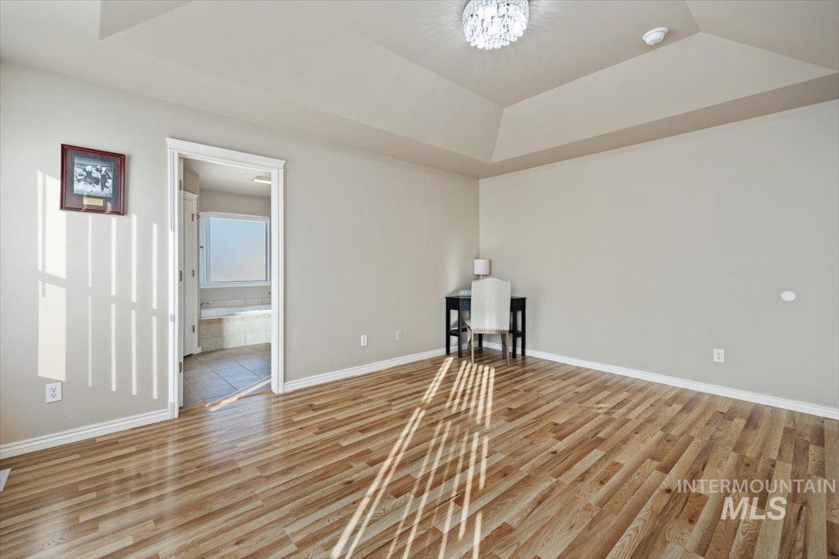 657 Creekside Way Twin Falls, ID 83301 - Photo 21 of 45 Empty room with a raised ceiling, light wood-style floors, and a chandelier