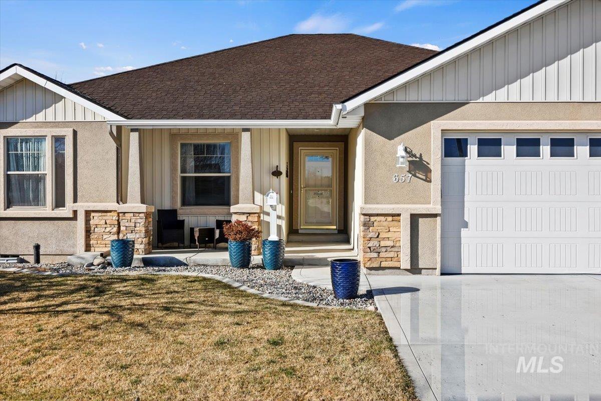 657 Creekside Way Twin Falls, ID 83301 - Photo 4 of 45 Entrance to property with stone siding, a yard, a shingled roof, and covered porch