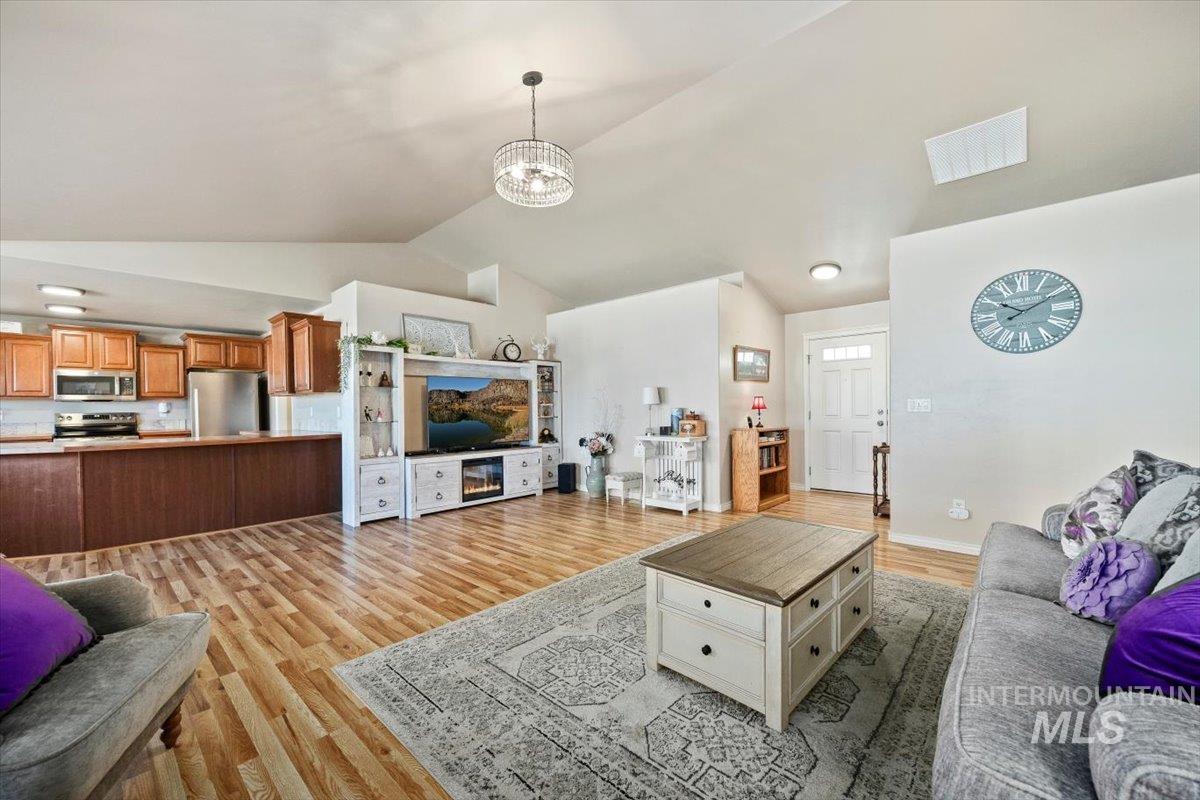 657 Creekside Way Twin Falls, ID 83301 - Photo 10 of 45 Living room with vaulted ceiling, light wood-style floors, and a chandelier