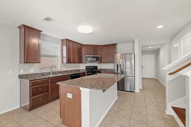 a large kitchen with stainless steel appliances granite countertop a stove refrigerator sink and cabinets