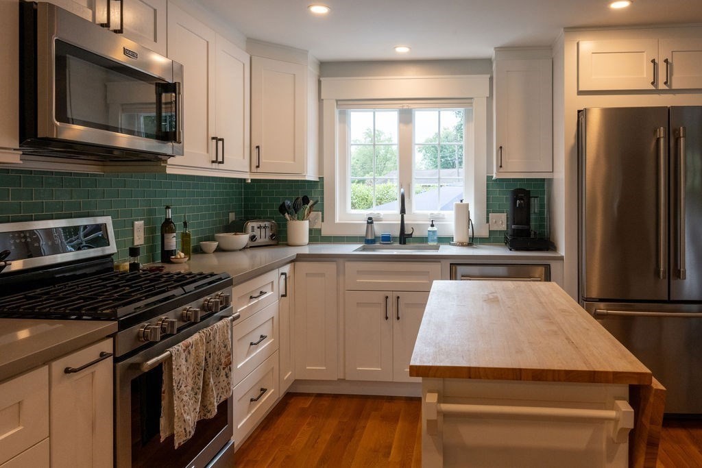 18 Belmore Road Natick, MA 01760 - Photo 19 of 30 a kitchen with kitchen island granite countertop a stove a sink and a microwave