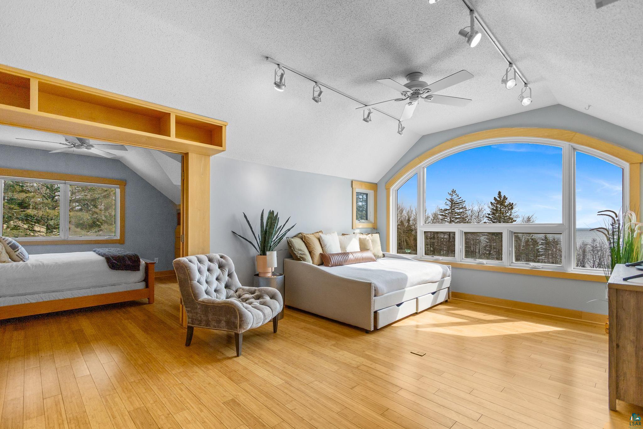5163 Greenwood Road Duluth, MN 55804 - Photo 24 of 47 Expansive arched window with broad outdoor scenery, vaulted ceiling, wood-finish flooring, ceiling fan, and track lighting