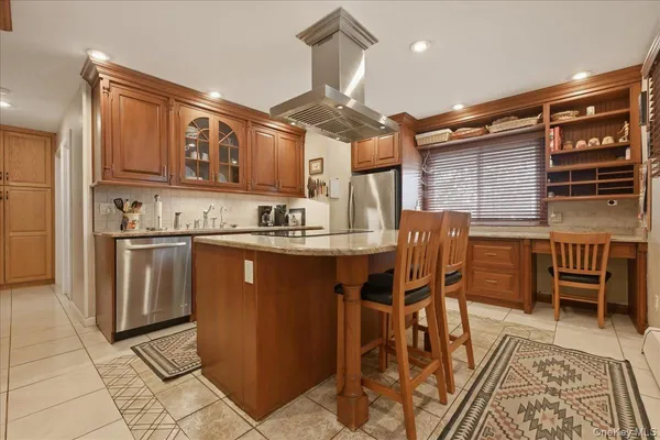 a kitchen with stainless steel appliances granite countertop a stove a sink dishwasher and a refrigerator with wooden cabinets