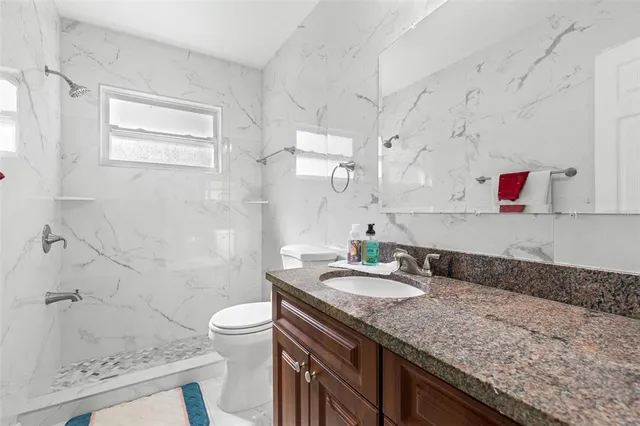 a bathroom with a granite countertop sink a toilet and shower