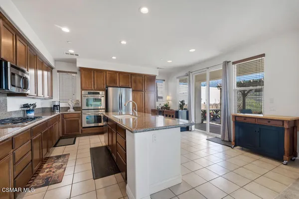 a kitchen with stainless steel appliances kitchen island granite countertop a refrigerator and a stove top oven