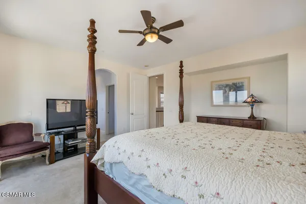 a bedroom with a bed a dresser and a chandelier