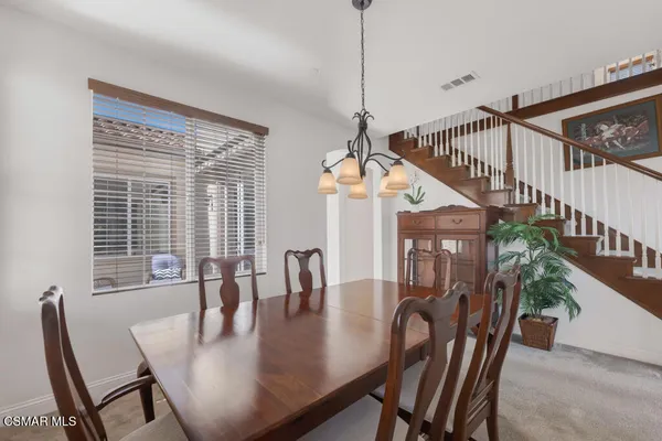 a view of a dining room and livingroom with furniture wooden floor a chandelier