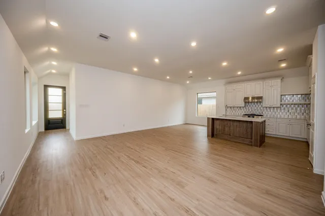 a view of kitchen with kitchen island wooden floors and stainless steel appliances