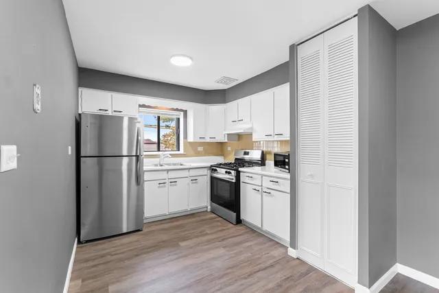 a kitchen with a refrigerator cabinets and wooden floor