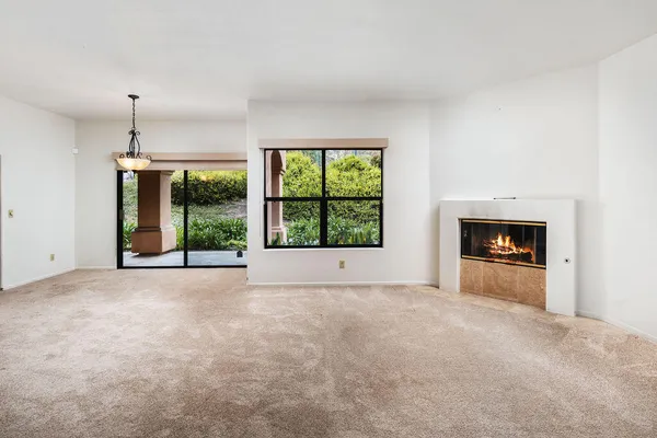 a view of an empty room with a window and fire place