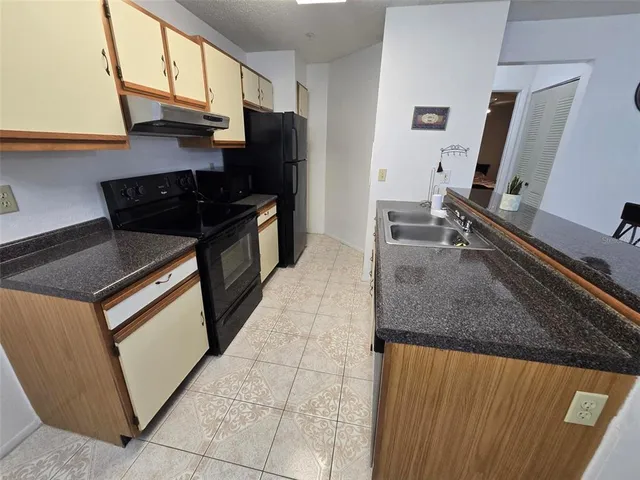a kitchen with granite countertop a sink a stove and refrigerator