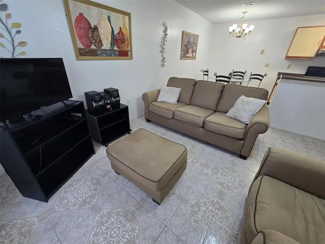 a living room with furniture a flat screen tv and a refrigerator