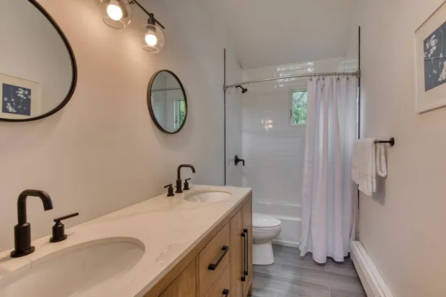 a bathroom with a double vanity sink mirror and toilet