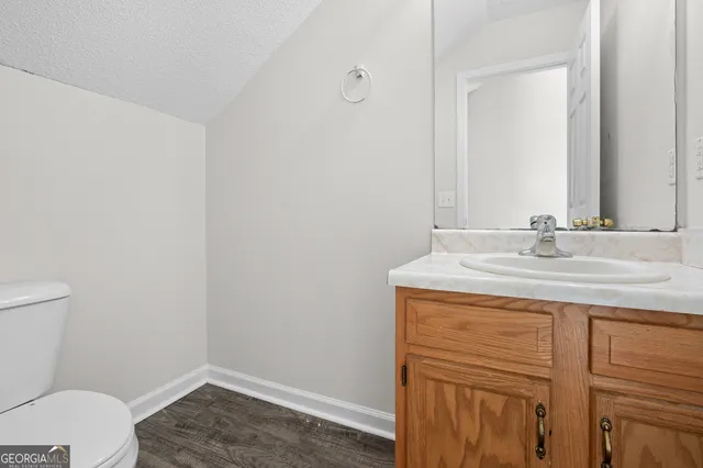 a bathroom with a granite countertop sink and a toilet