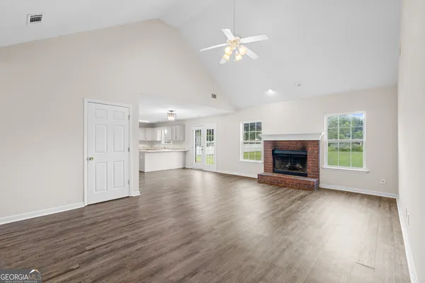 an empty room with wooden floor fireplace and windows