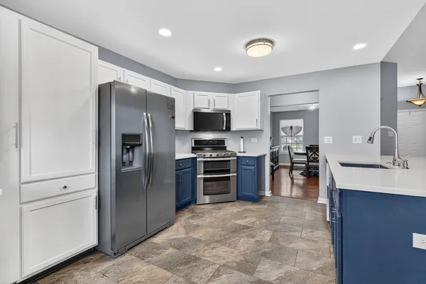 a kitchen with stainless steel appliances kitchen island granite countertop a stove top oven a sink a counter space and cabinets