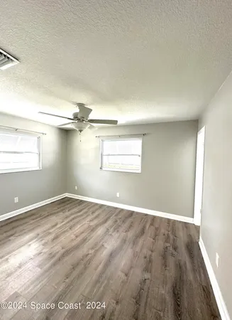 a view of empty room with wooden floor and fan