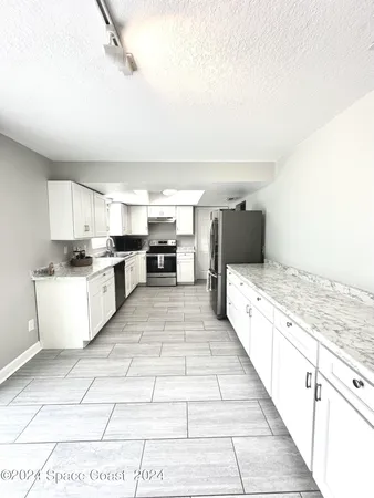 a large white kitchen with stainless steel appliances granite countertop a stove and cabinets