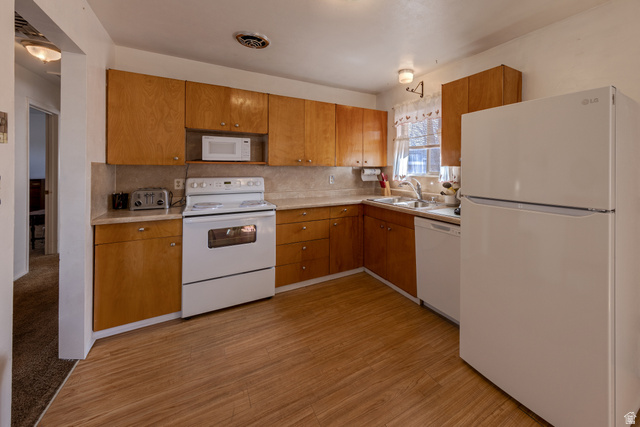738 Locust Lane Moab, UT 84532 - Photo 8 of 25 Kitchen featuring white appliances, light countertops, backsplash, and light wood-type flooring