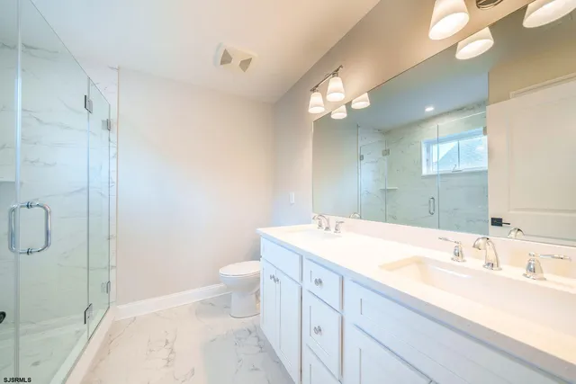 a bathroom with a granite countertop sink a toilet and a shower