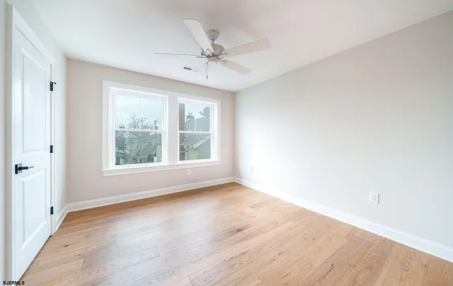 an empty room with wooden floor fan and windows