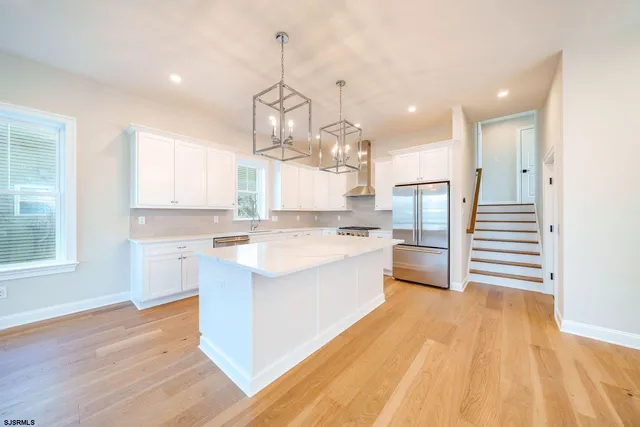 a large kitchen with kitchen island white cabinets and stainless steel appliances
