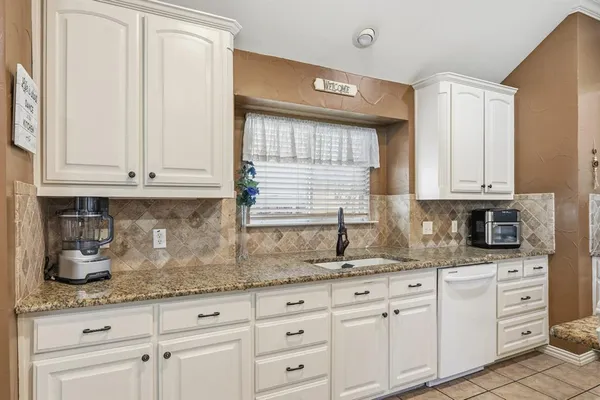 a large white kitchen with a stove a refrigerator a dining table and chairs