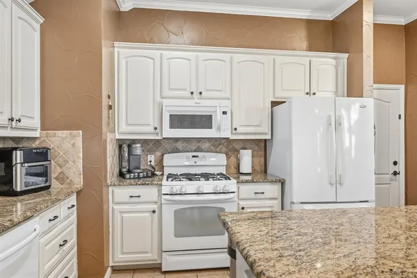 a kitchen with granite countertop white cabinets and white appliances