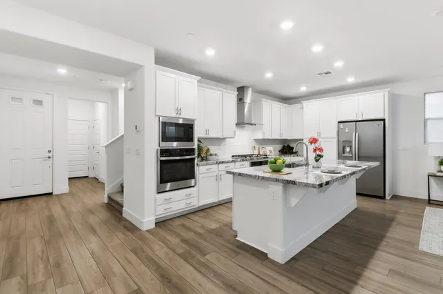 a kitchen with stainless steel appliances kitchen island granite countertop a stove and a refrigerator